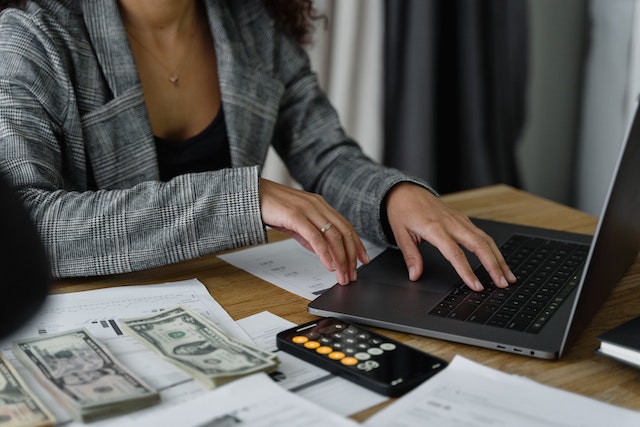 someone counting money next to a laptop